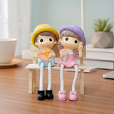 TM0024 Cute Couple Dolls Sitting on Bench with Dangling Legs - Resin Showpiece for Home Decor & Gifting